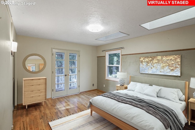 bedroom featuring access to outside, french doors, a textured ceiling, and wood finished floors