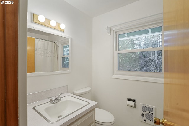 bathroom with a shower with shower curtain, heating unit, toilet, and vanity