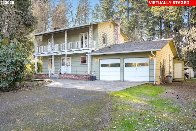 front of property featuring a balcony, covered porch, a garage, and driveway