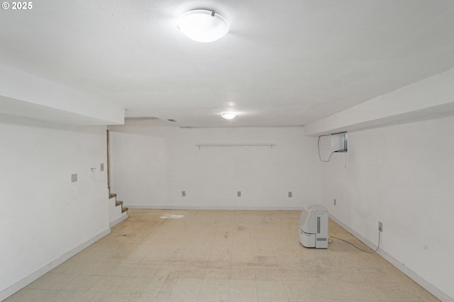 finished basement with baseboards, light floors, and stairs