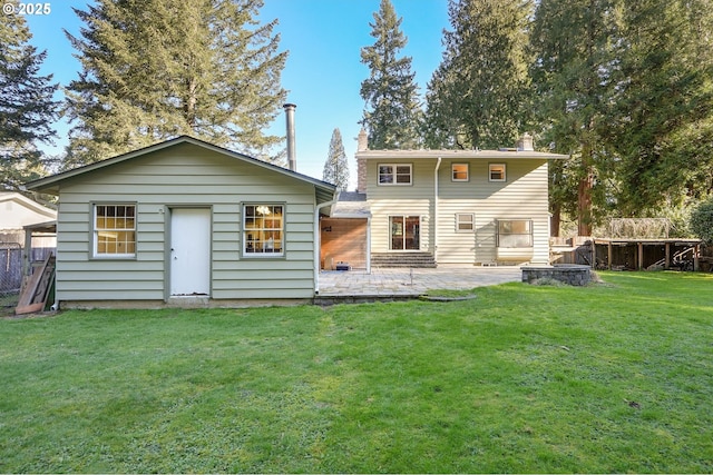 back of property with a patio area, a yard, fence, and a chimney