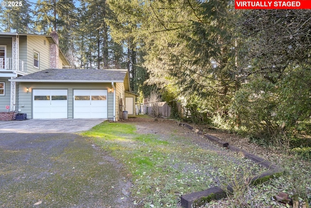 view of yard featuring driveway, an attached garage, and fence