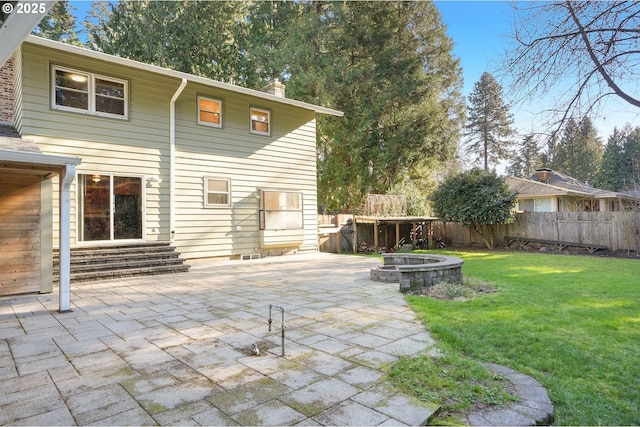 back of house with fence, an outdoor fire pit, a yard, a chimney, and a patio area