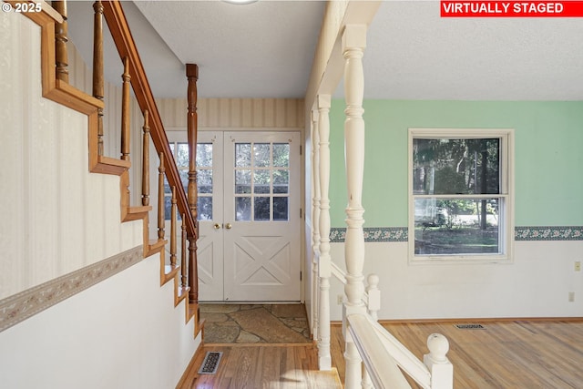 doorway featuring visible vents, a textured ceiling, stairs, and wood finished floors