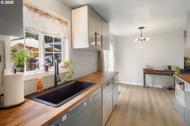 3426 Royal Ave, Eugene, OR 97402 - kitchen with wooden counters, a sink, light wood-style flooring, a chandelier, and pendant lighting