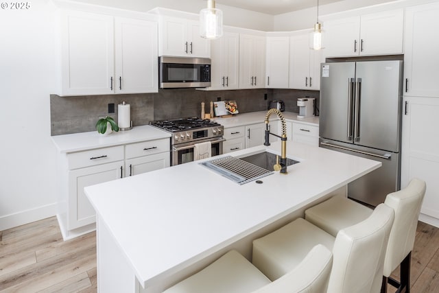 19386 Juniper Ct, Oregon City, OR 97045 - kitchen featuring a sink, a kitchen breakfast bar, light wood-style flooring, stainless steel appliances, and decorative backsplash