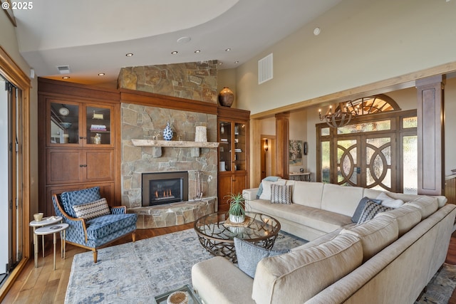 280 Fall Creek Dr, Oceanside, OR 97134 - living area featuring high vaulted ceiling, wood finished floors, a chandelier, decorative columns, and a stone fireplace
