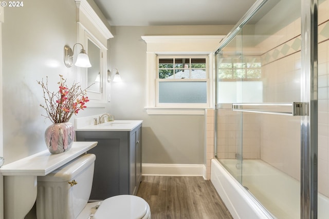 full bathroom with toilet, bath / shower combo with glass door, vanity, and hardwood / wood-style floors