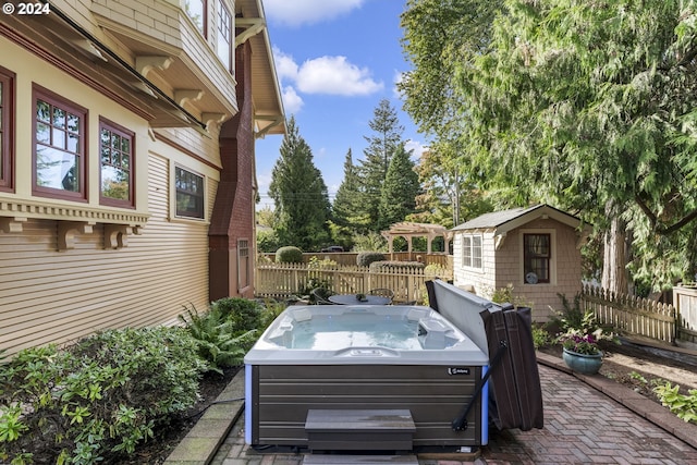 view of patio with a hot tub and a storage unit