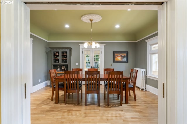 dining space featuring a notable chandelier, light hardwood / wood-style floors, radiator heating unit, and plenty of natural light