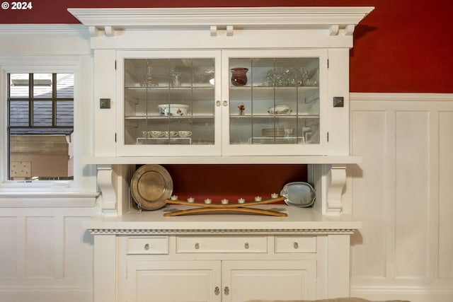 bar featuring white cabinetry and ornamental molding