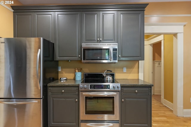 kitchen featuring appliances with stainless steel finishes, gray cabinetry, light hardwood / wood-style flooring, and crown molding