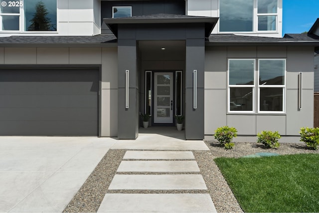 6803 NW 24th Ct, Vancouver, WA 98665 - view of exterior entry with a shingled roof, a garage, concrete driveway, and stucco siding