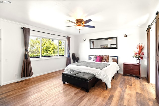 32890 Hillside Acres Rd, Gold Beach, OR 97444 - bedroom with a barn door, visible vents, baseboards, ornamental molding, and wood finished floors