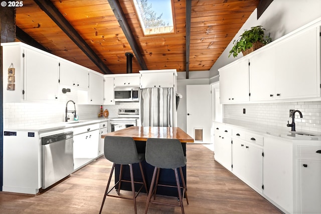 32890 Hillside Acres Rd, Gold Beach, OR 97444 - kitchen featuring a sink, wooden ceiling, vaulted ceiling with skylight, backsplash, and appliances with stainless steel finishes