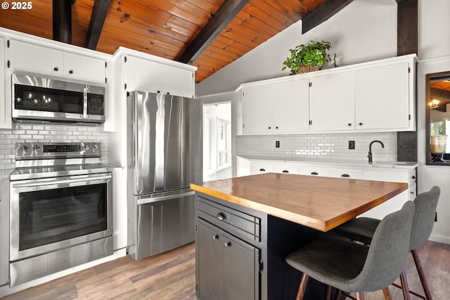 32890 Hillside Acres Rd, Gold Beach, OR 97444 - kitchen with stainless steel appliances, light wood-style floors, vaulted ceiling with beams, wood ceiling, and white cabinets