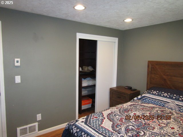 bedroom featuring hardwood / wood-style floors, a closet, and a textured ceiling