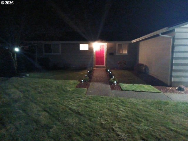 exterior entry at twilight featuring a lawn