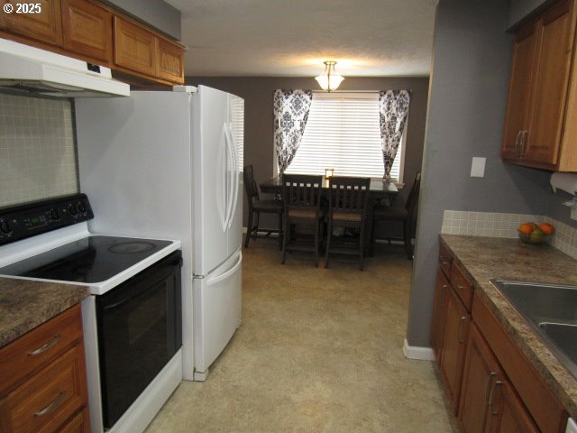 kitchen with a textured ceiling, electric range, backsplash, and dark stone counters