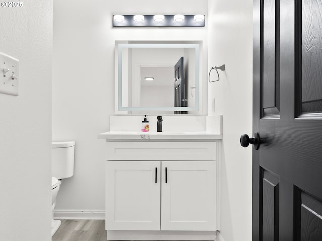 bathroom with vanity, toilet, and hardwood / wood-style floors