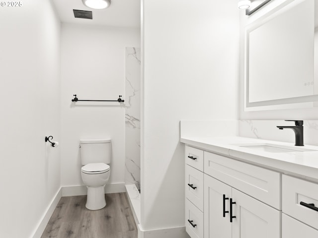 bathroom with walk in shower, vanity, toilet, and wood-type flooring