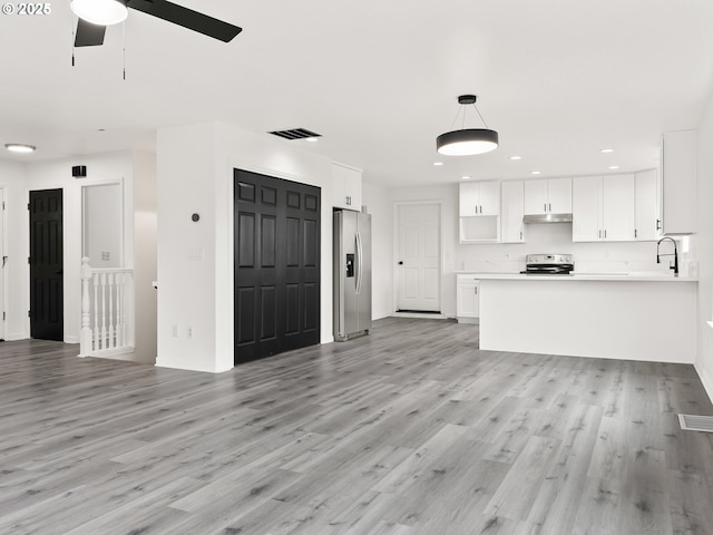 unfurnished living room with sink, ceiling fan, and light wood-type flooring