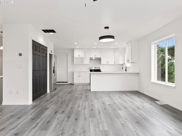 kitchen with pendant lighting, light hardwood / wood-style flooring, appliances with stainless steel finishes, white cabinets, and kitchen peninsula