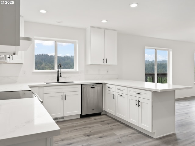 kitchen featuring sink, white cabinetry, stainless steel dishwasher, kitchen peninsula, and light wood-type flooring