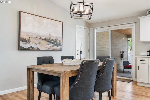 dining area with light wood finished floors, baseboards, and an inviting chandelier