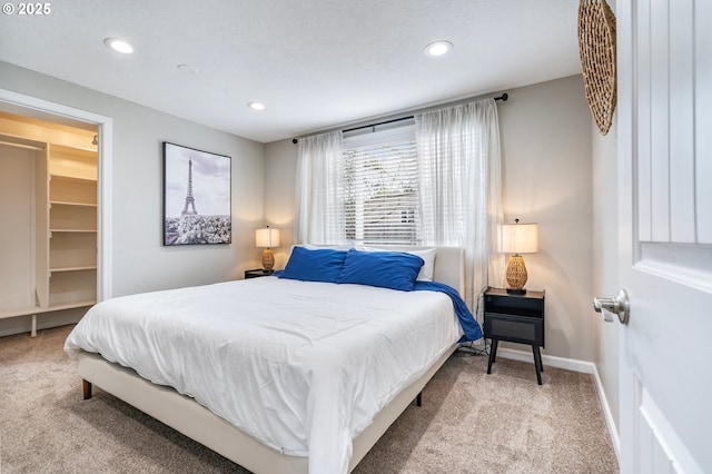 carpeted bedroom with a spacious closet, recessed lighting, and baseboards