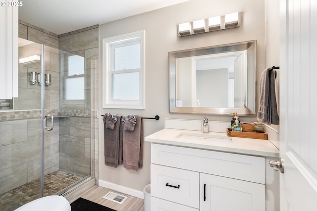 full bathroom with vanity, visible vents, toilet, a stall shower, and baseboards