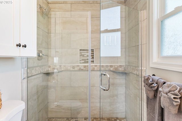 bathroom with toilet, a stall shower, and a wealth of natural light