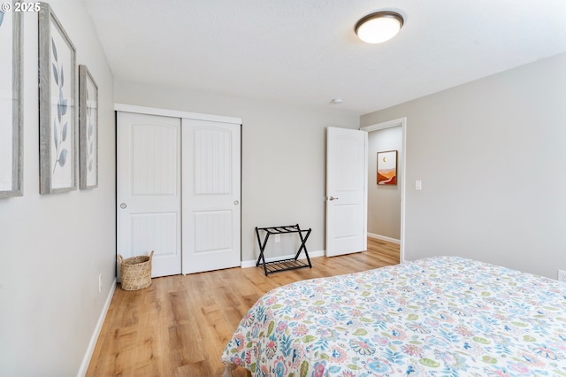 bedroom featuring light wood-type flooring, a closet, and baseboards