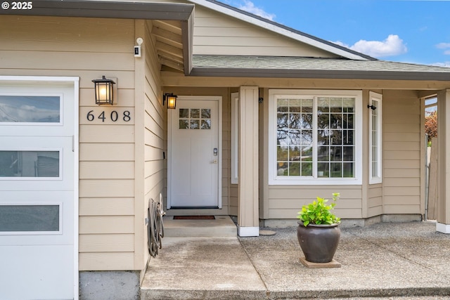 view of exterior entry featuring a shingled roof