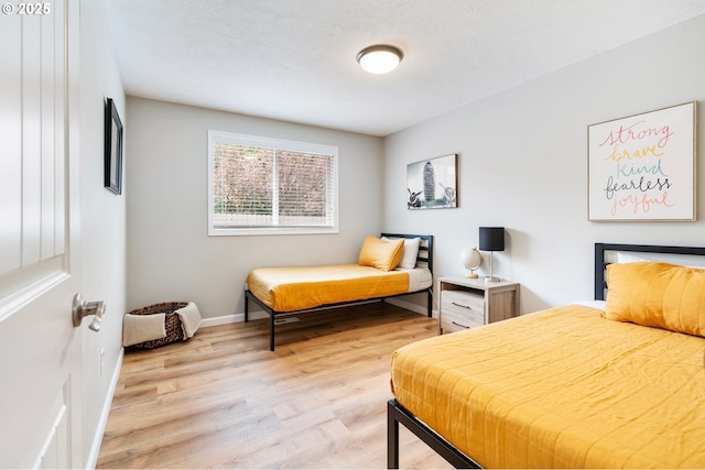 bedroom featuring light wood finished floors and baseboards