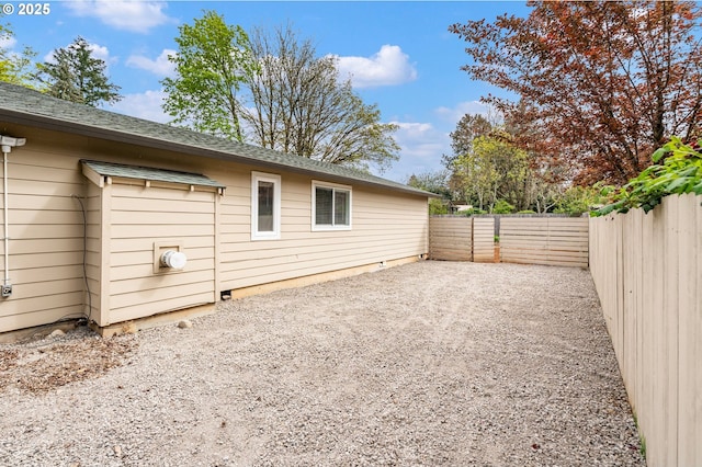 view of property exterior with a patio area, roof with shingles, and a fenced backyard