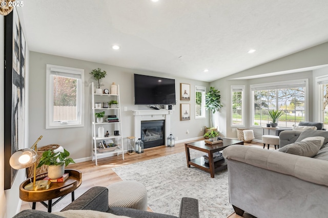 living room featuring a glass covered fireplace, recessed lighting, light wood finished floors, and baseboards