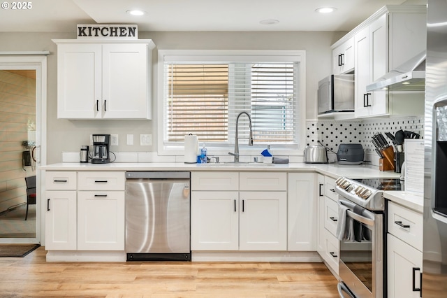 kitchen featuring white cabinetry, appliances with stainless steel finishes, under cabinet range hood, light countertops, and a sink