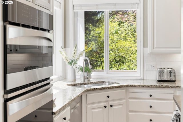 kitchen featuring a sink, white cabinetry, tasteful backsplash, and a warming drawer