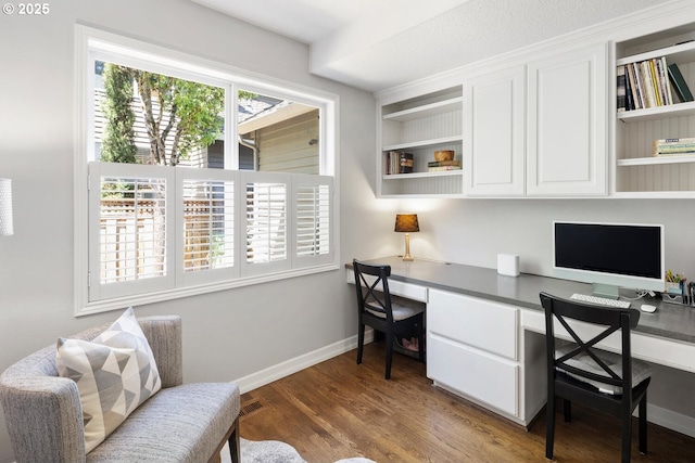 office space featuring built in desk, wood finished floors, and baseboards