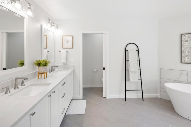 bathroom featuring double vanity, a soaking tub, tile patterned floors, and baseboards