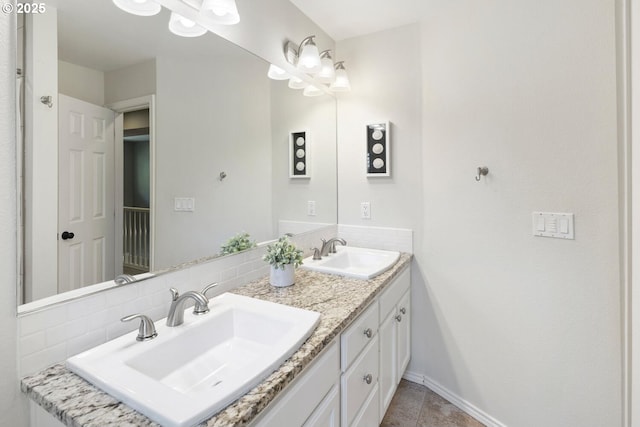 bathroom featuring double vanity, tasteful backsplash, baseboards, and tile patterned floors