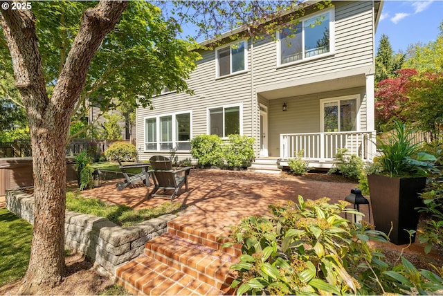rear view of property featuring a porch, fence, and a patio area