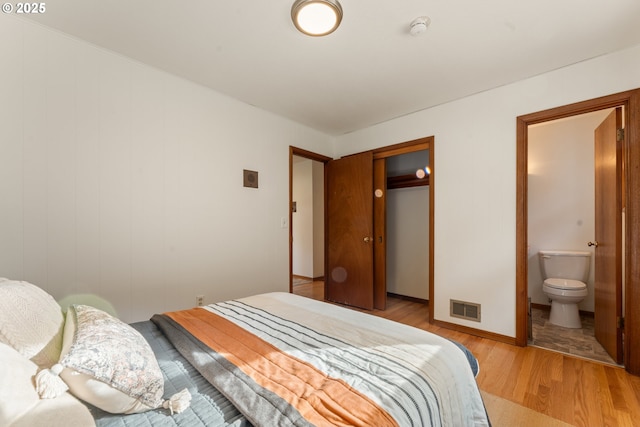 bedroom featuring light wood-type flooring, visible vents, a closet, and ensuite bathroom