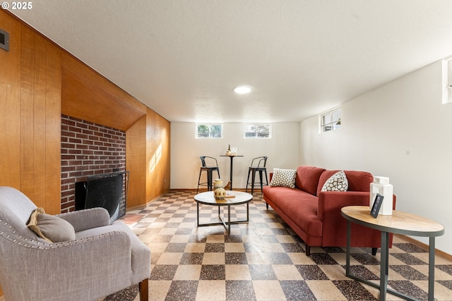 living area with a brick fireplace, baseboards, a textured ceiling, and tile patterned floors