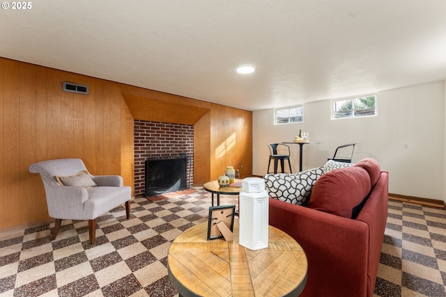 living area with wooden walls, visible vents, a fireplace, and tile patterned floors