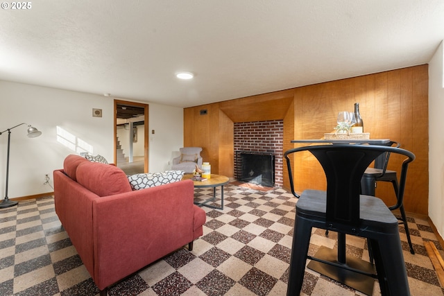 living area featuring a fireplace, wooden walls, a textured ceiling, baseboards, and tile patterned floors