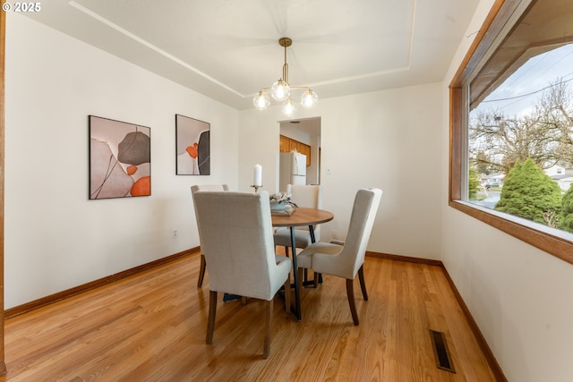 dining area with light wood finished floors, baseboards, and visible vents