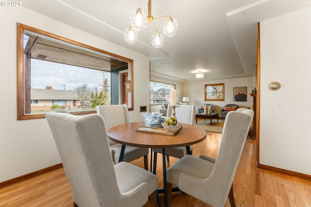 dining room featuring a chandelier, light wood finished floors, and baseboards