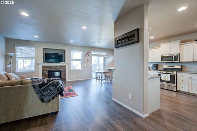 1531 Washington St, Independence, OR 97351 - living room with dark wood-style floors, baseboards, a glass covered fireplace, recessed lighting, and a textured ceiling
